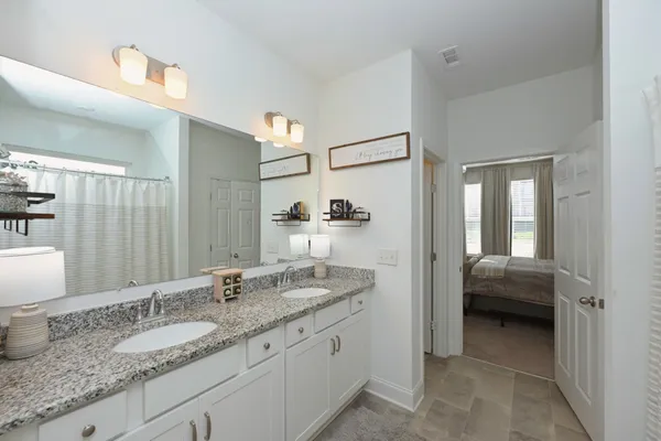 a en suite bathroom with a granite countertop sink and a mirror