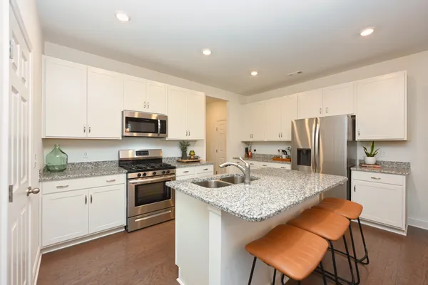 a kitchen with kitchen island granite countertop a stove sink microwave and refrigerator