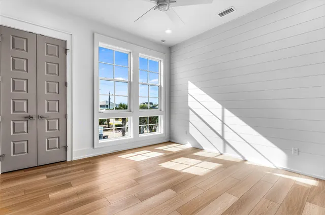a view of an empty room with a window and wooden floor
