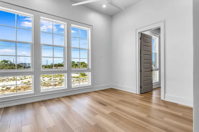 an empty room with wooden floor and windows