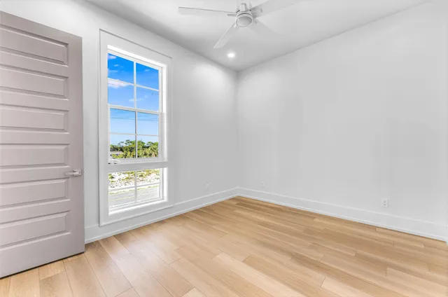 a view of an empty room with a window and wooden floor