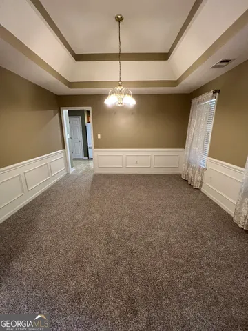 a view of an empty room with window and chandelier fan