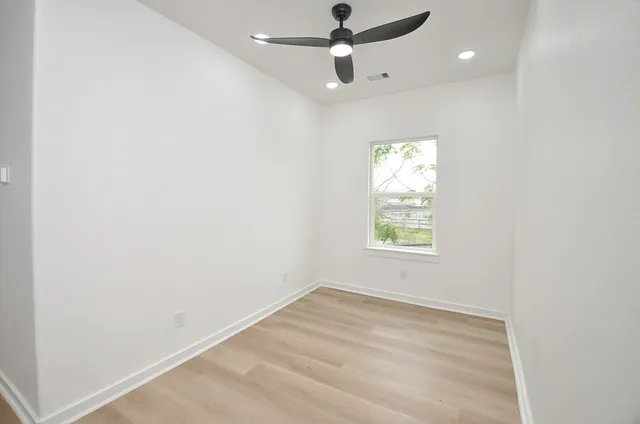 an empty room with a window and a ceiling fan