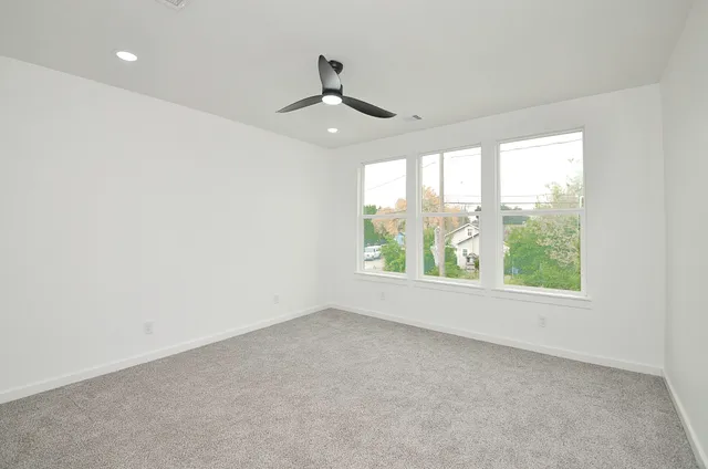 an empty room with windows and ceiling fan