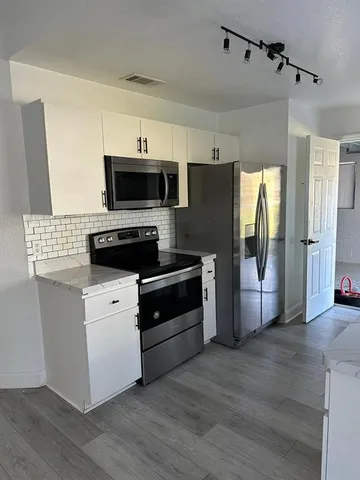 a kitchen with stainless steel appliances a stove a microwave and white cabinets