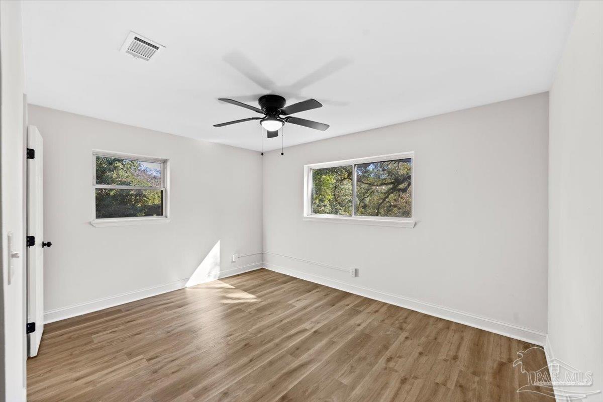 5149 Crestwood Road Pensacola, FL 32503 - Photo 22 of 53 a view of an empty room with wooden floor and a ceiling fan