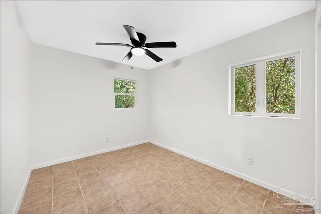 an empty room with windows and fan