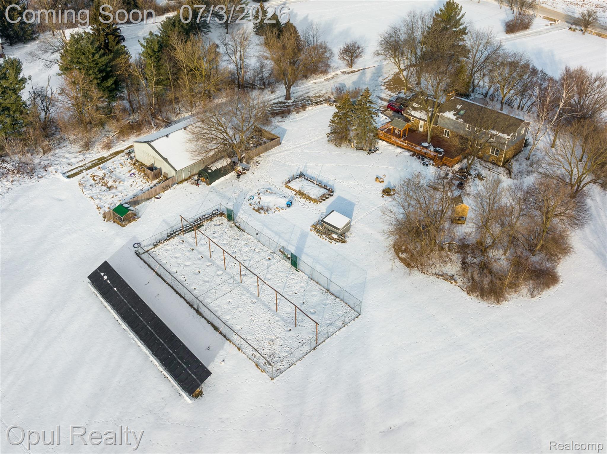 8855 Gross Road Dexter, MI 48130 - Photo 13 of 53 Expansive property featuring a residence with a large deck, a substantial outbuilding, a long structure with a dark roof, and a fenced enclosure