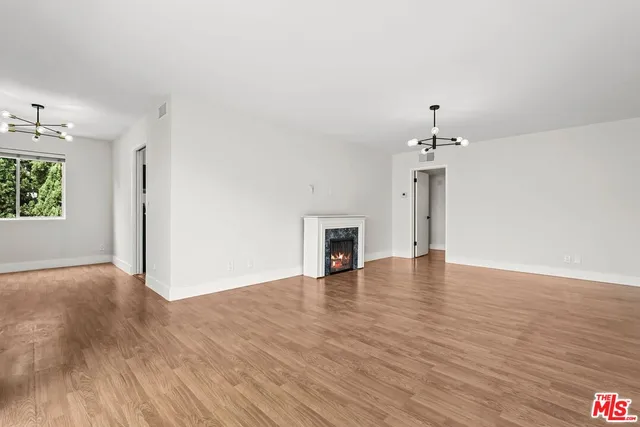 an empty room with wooden floor chandelier and windows