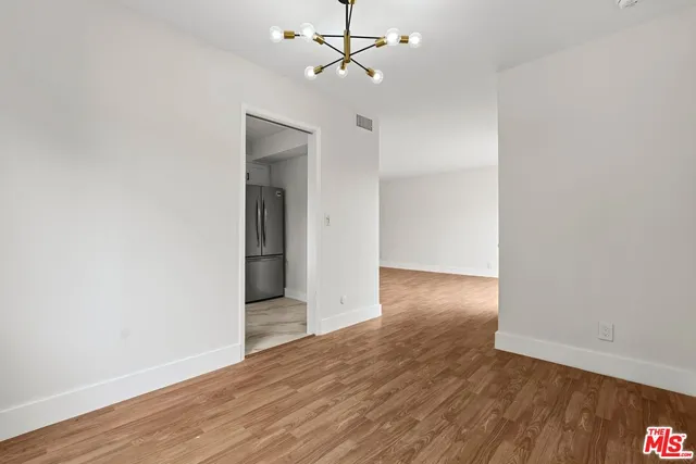 an empty room with wooden floor ceiling fan and window