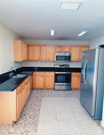 a large kitchen with granite countertop a stove top oven a sink dishwasher a refrigerator and a granite counter tops