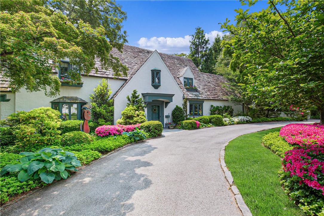 a front view of a house with a yard and fountain in middle of the road