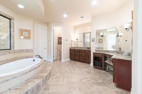 a spacious bathroom with a tub sink shower and mirror