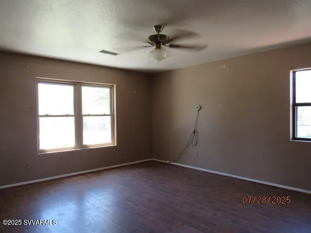 an empty room with wooden floor chandelier fan and windows