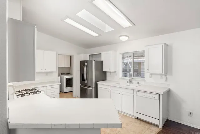 a large white kitchen with stainless steel appliances