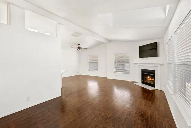 an empty room with wooden floor fireplace and windows