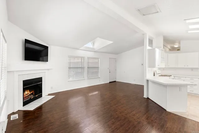 a view of empty room with wooden floor and a fireplace