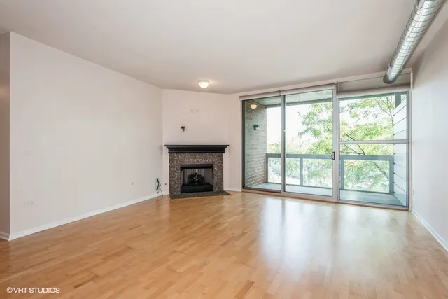 a view of empty room with wooden floor and fireplace