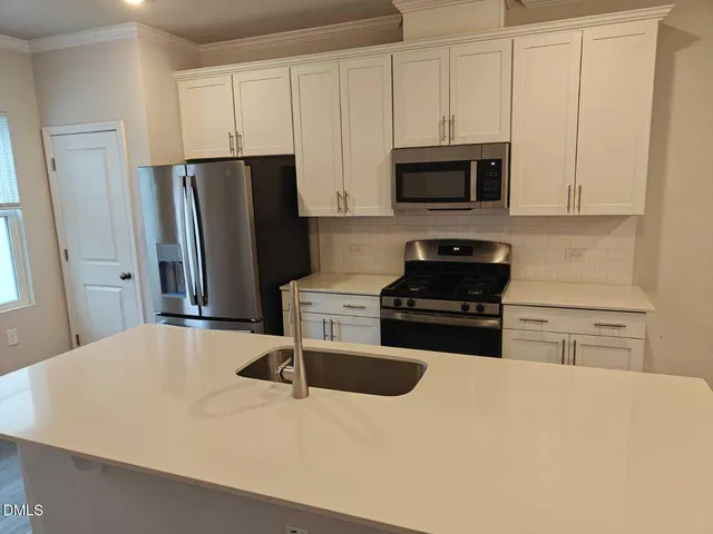 a kitchen with granite countertop a refrigerator stove and microwave