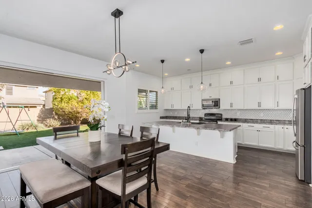 a kitchen with stainless steel appliances granite countertop a stove a refrigerator a kitchen island a sink and a table