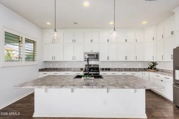 a kitchen with kitchen island granite countertop a stove a sink a counter space and a window