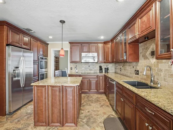 a kitchen with stainless steel appliances granite countertop a sink stove and refrigerator