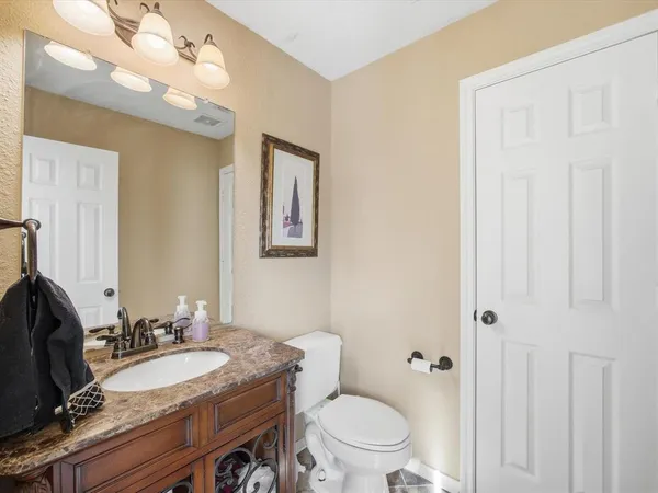 a bathroom with a granite countertop sink a toilet and a mirror