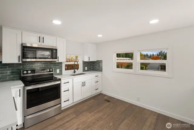 a kitchen with white cabinets and appliances