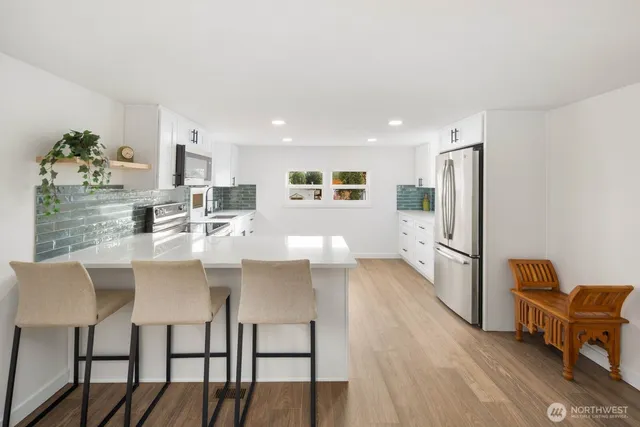 a kitchen with stainless steel appliances a microwave a sink a stove a table and chairs