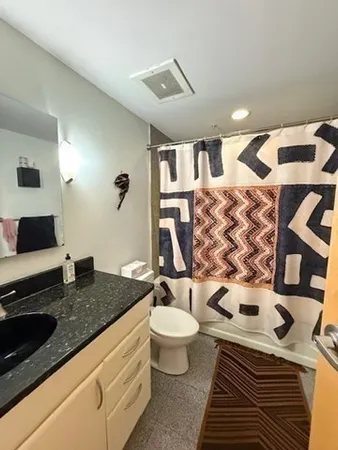a bathroom with a granite countertop toilet sink and mirror