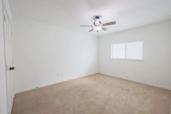 an empty room with a window and a fan