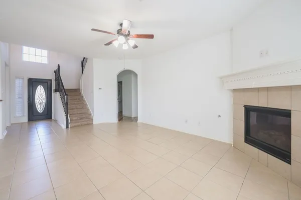 a view of an empty room with chandelier fan and fireplace