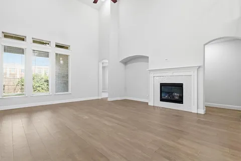 a view of an empty room with wooden floor fireplace and a window