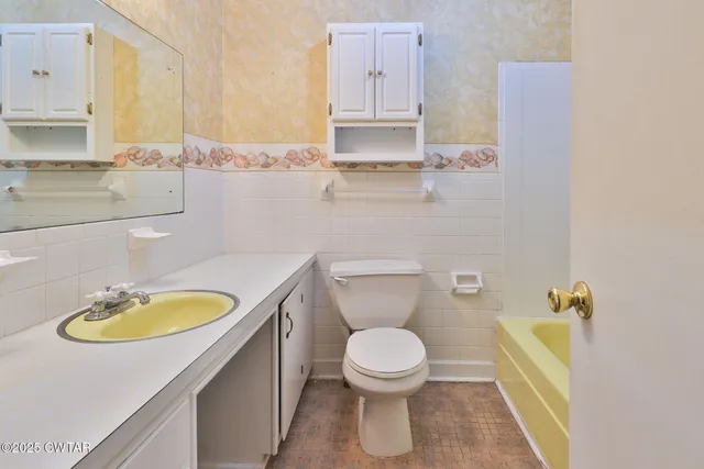 a bathroom with a granite countertop toilet sink and mirror