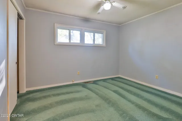 an empty room with a chandelier fan and windows