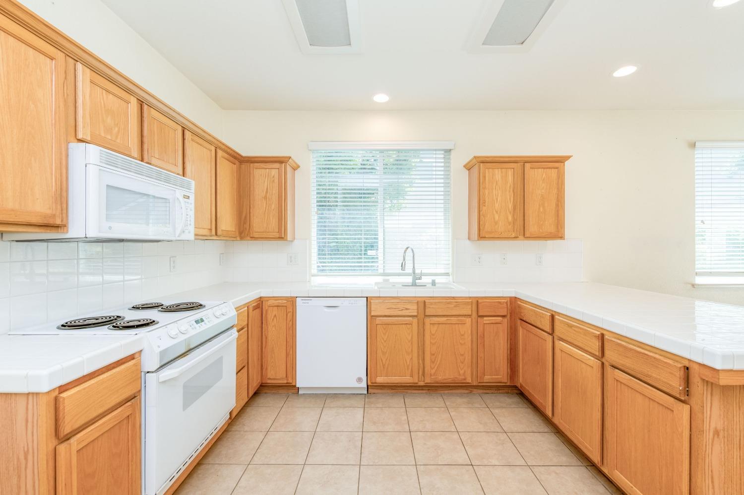 694 West Lisbon Lane Clovis, CA 93619 - Photo 13 of 39 a large kitchen with stainless steel appliances granite countertop a sink and cabinets