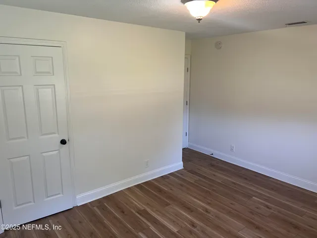 a view of an empty room with wooden floor