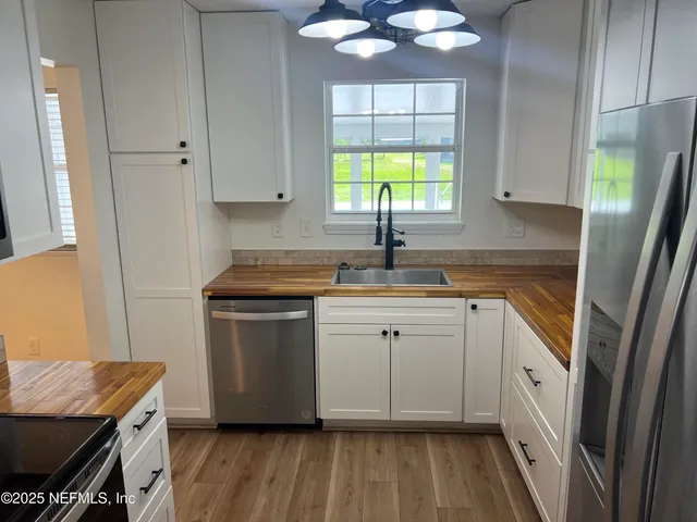 a kitchen with a sink appliances cabinets and a window
