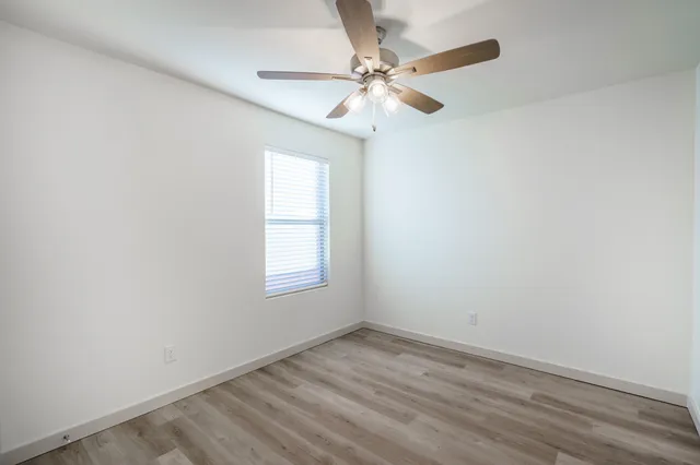 an empty room with a window and a fan
