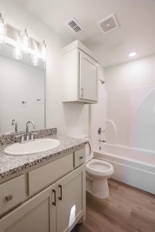 a bathroom with a granite countertop toilet sink and mirror