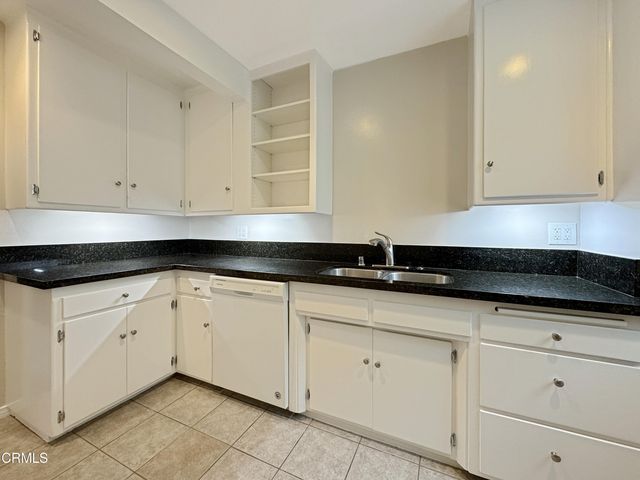 a kitchen with granite countertop white cabinets and a sink