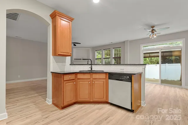 a kitchen with stainless steel appliances granite countertop a sink a stove a refrigerator and island with wooden floor