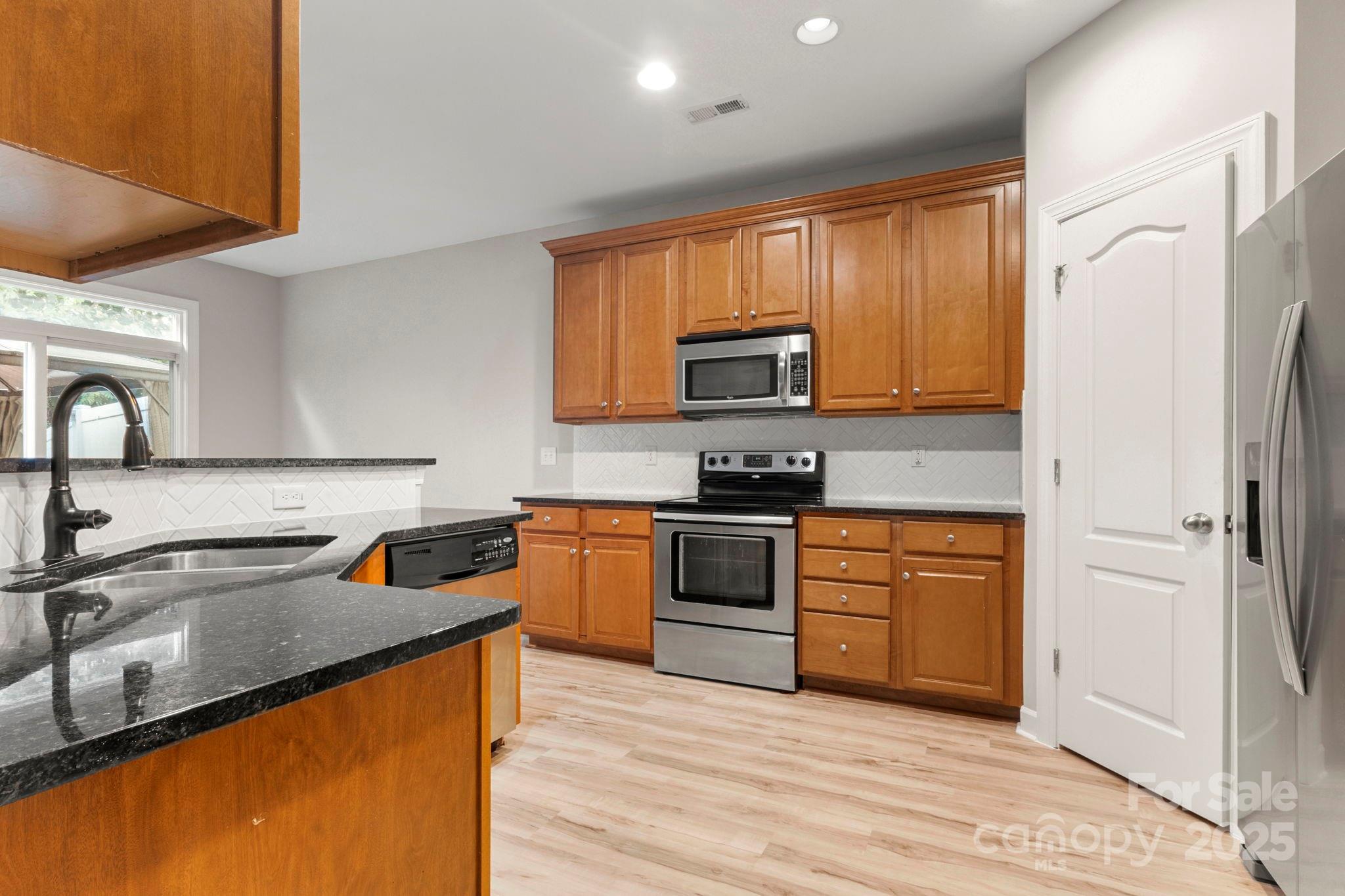 6927 Maricopa Road Charlotte, NC 28277 - Photo 12 of 32 a kitchen with stainless steel appliances granite countertop a sink stove and refrigerator