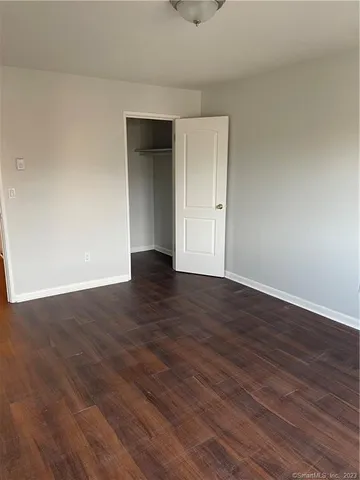 a view of an empty room with wooden floor and closet