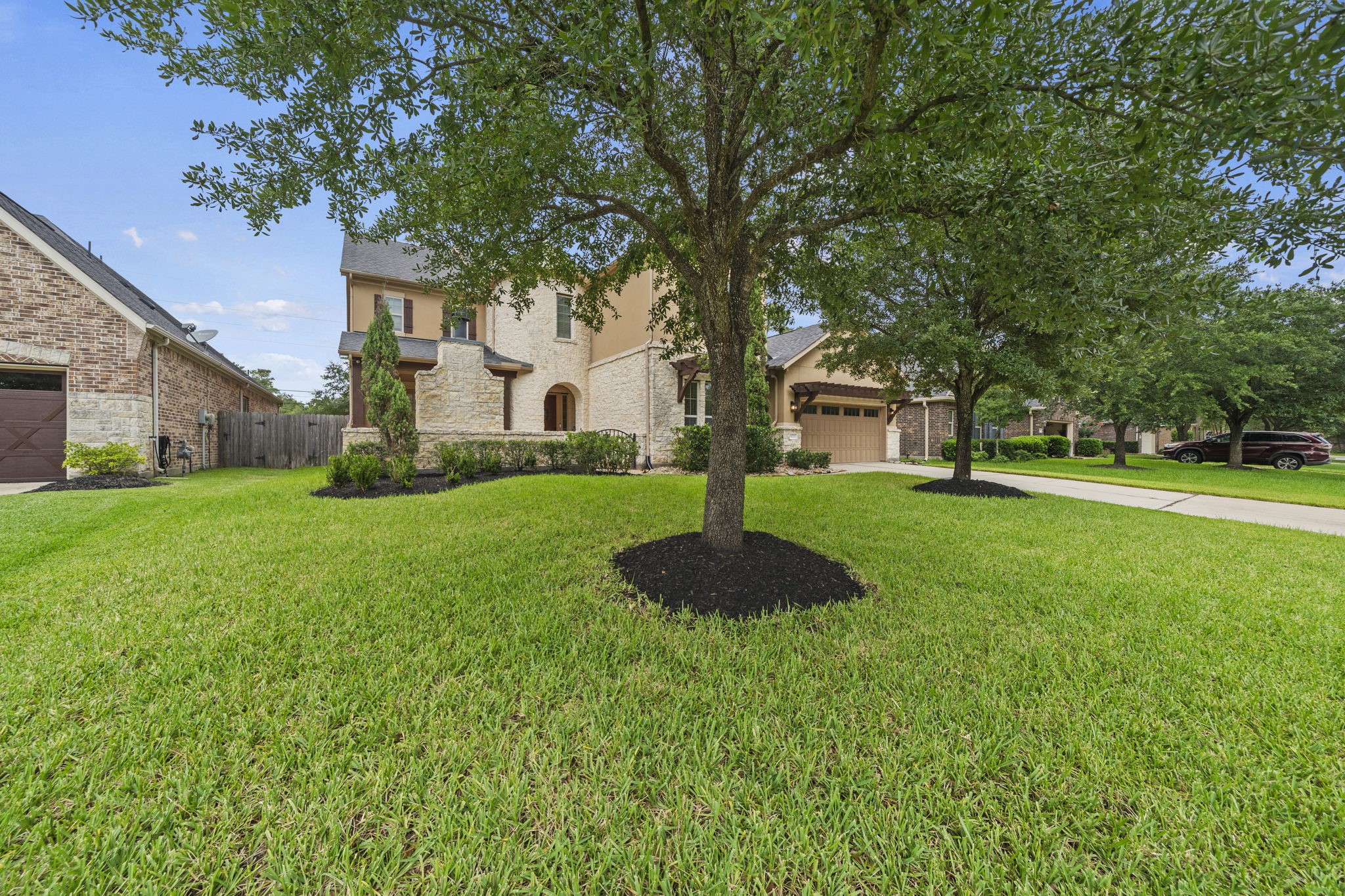 14215 Spindle Arbor Road Cypress, TX 77429 - Photo 44 of 47 Charming two-story home with a stone and brick exterior, situated on a spacious, well-maintained lawn with mature trees. The property features a driveway leading to a two-car garage, creating a welcoming and attractive curb appeal in a suburban neighborhood.