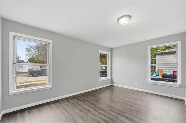 a view of an empty room with a window and wooden floor