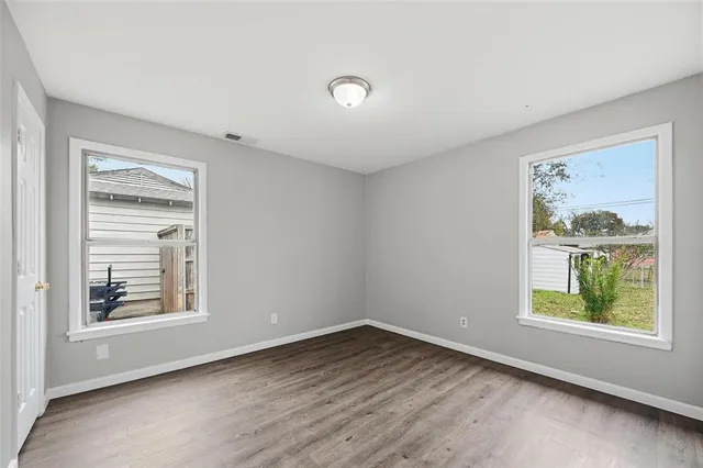 a view of an empty room with a window and wooden floor