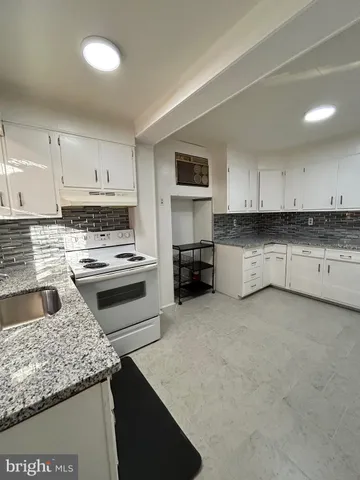 a kitchen with granite countertop a stove sink and cabinets