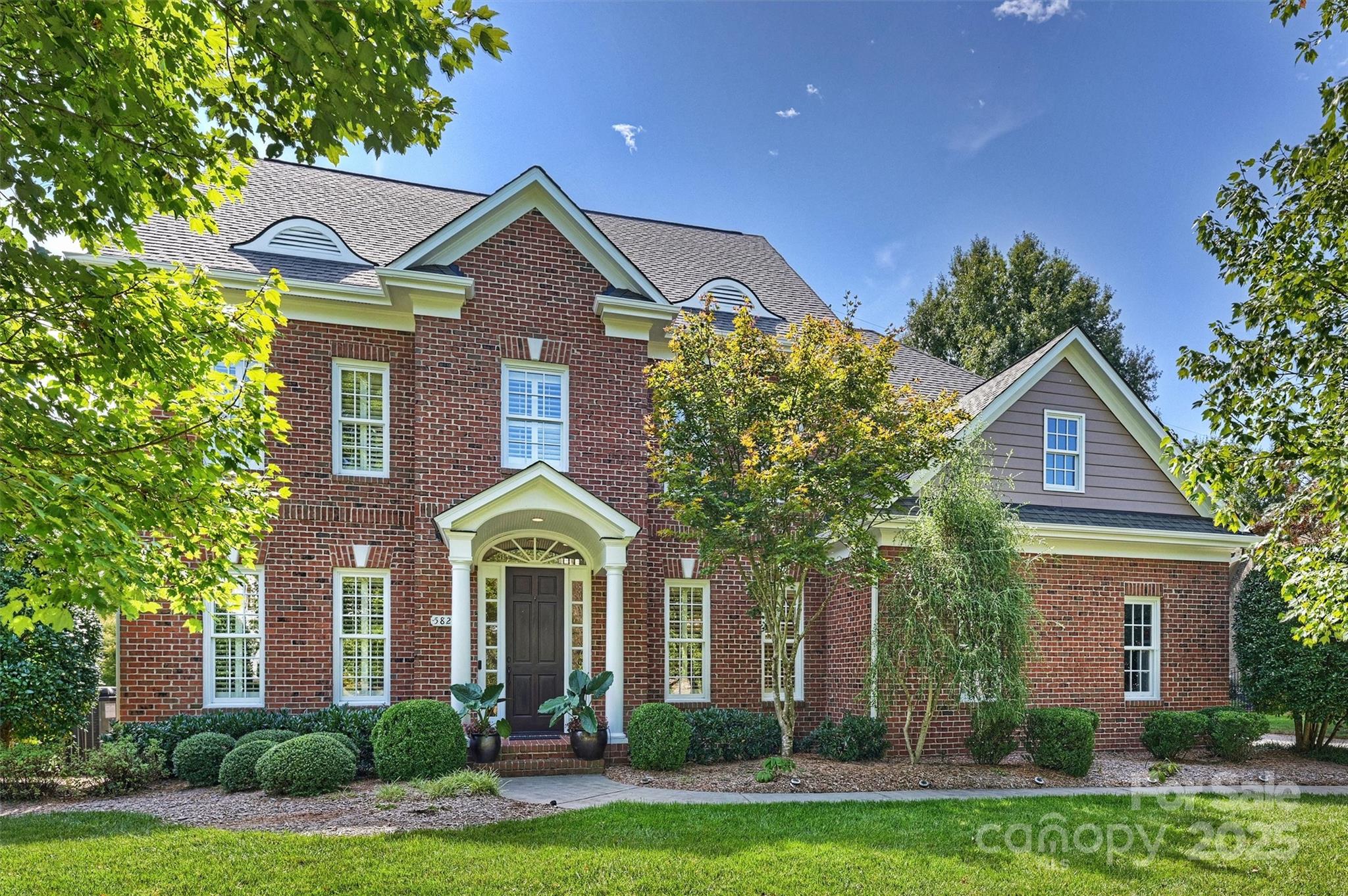 a front view of a house with a yard and potted plants