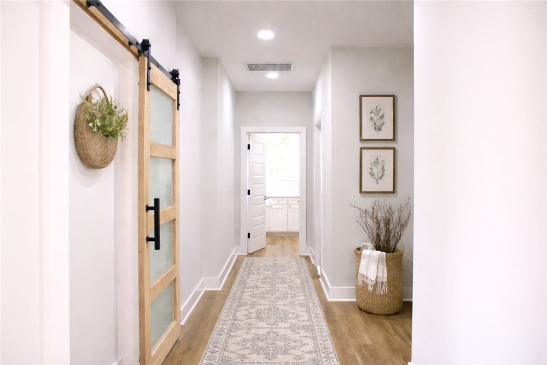 2515 Highway 29 Anderson, SC 29621 - Photo 14 of 38 A long, bright hallway features a modern barn door and light wood flooring, leading to an interior room with white cabinetry.